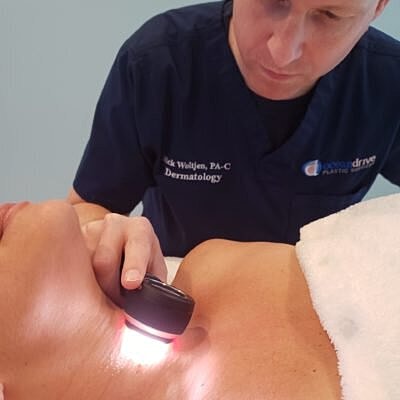 Dermatologist conducting skin examination with device.