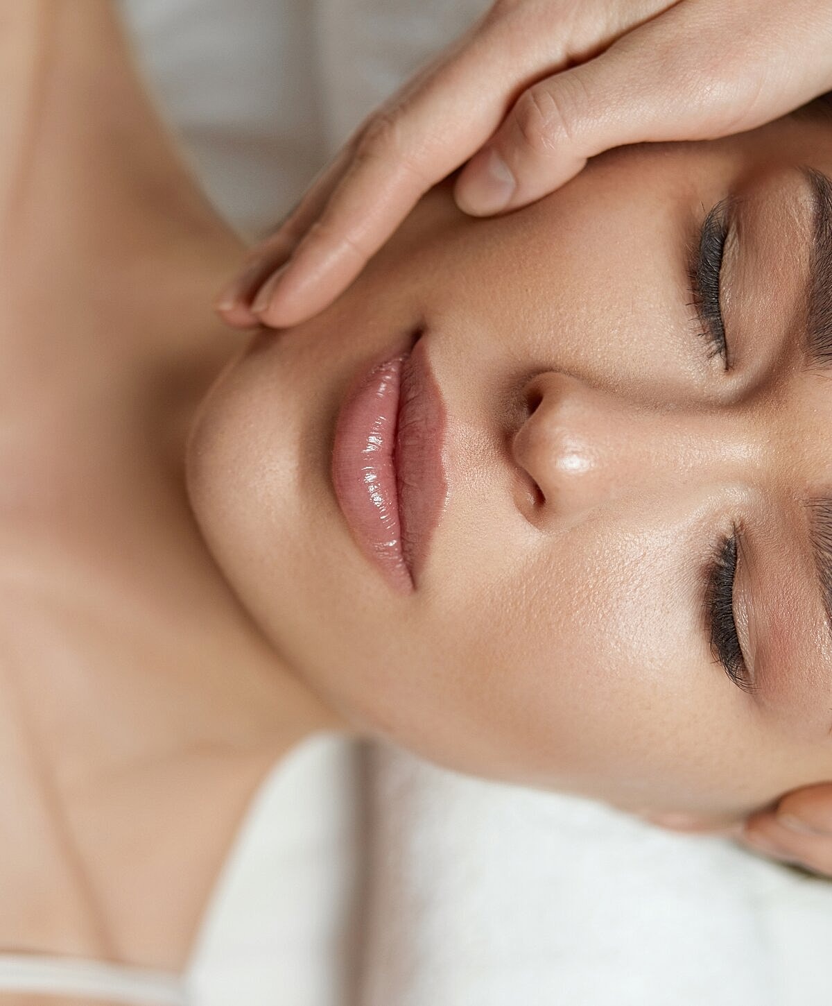 Close-up of serene woman receiving facial treatment.