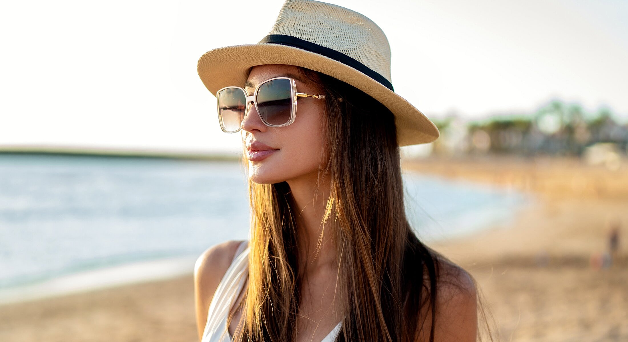 Woman with sunglasses and hat at the beach.