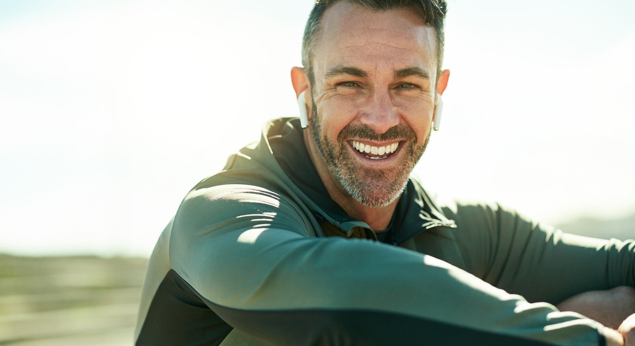 Smiling man in athletic gear with earbuds.