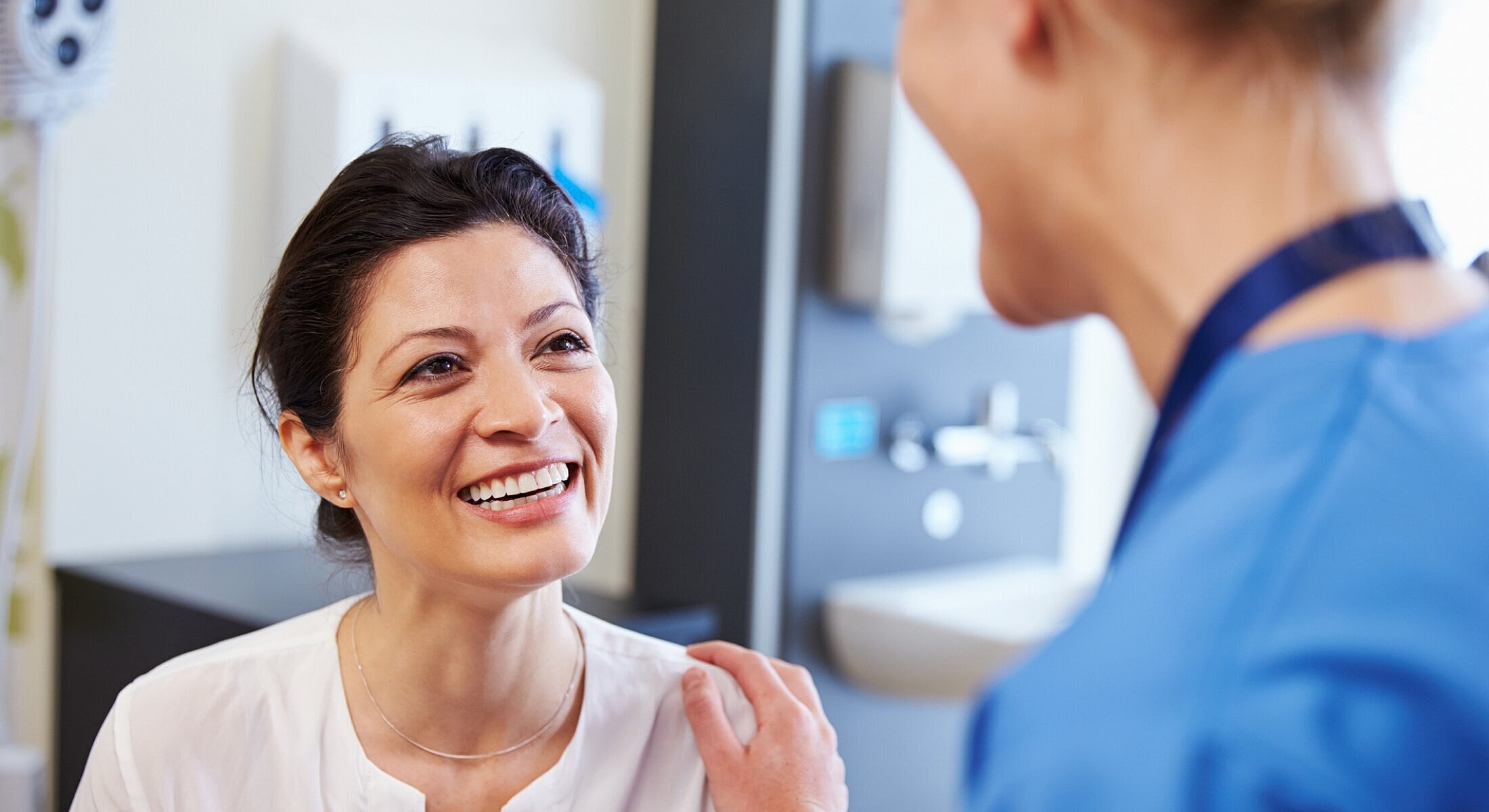 Smiling patient interacts with healthcare professional.